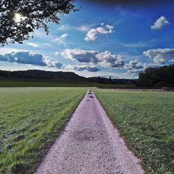 Road amidst field against sky