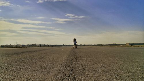 Rear view of man walking on road against sky