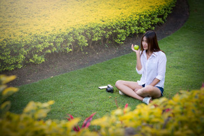 High angle view of young woman having apple while sitting at park