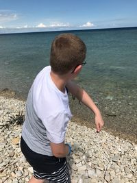 Boy standing on beach against sky