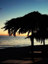 Silhouette palm trees on beach against clear sky