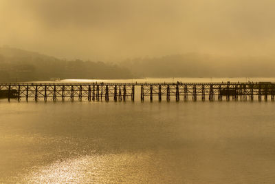 Pier over sea against sky during sunset