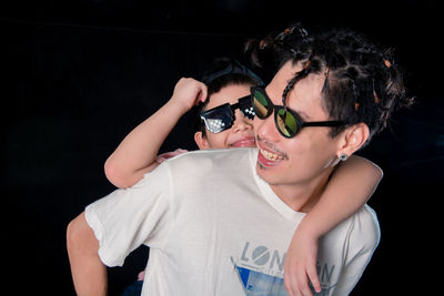 Man and little boy with sunglasses standing looking camera on dark studio background , asian family