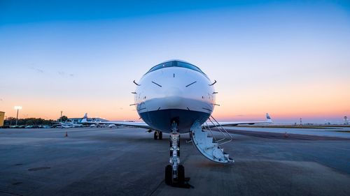 Airplane on runway against sky during sunset