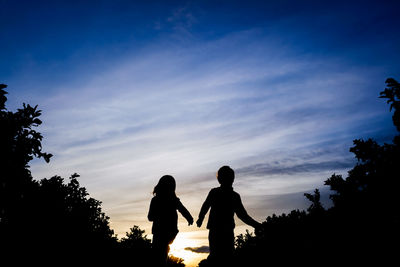 Silhouette kids against sky during sunset