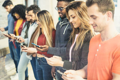 Friends using smart phones in city