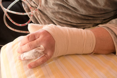 Midsection of person with broken hand at home