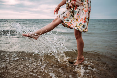 Young girl in dress splashing water in lake michigan