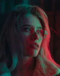 Close-up of girl wearing eyeglasses in darkroom