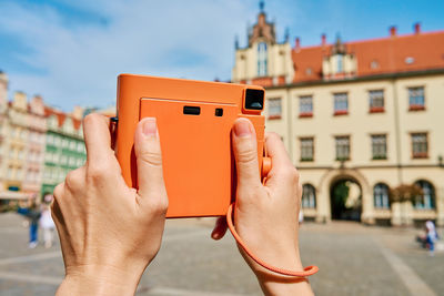 Female tourist captures memories during travel with vintage instant camera