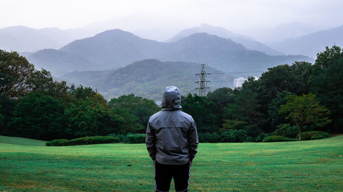 Rear view of man standing on mountain against sky