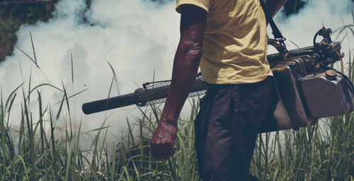 Midsection of man holding plants on field