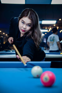 Portrait of young woman playing pool