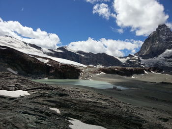 Scenic view of mountains against cloudy sky on sunny day