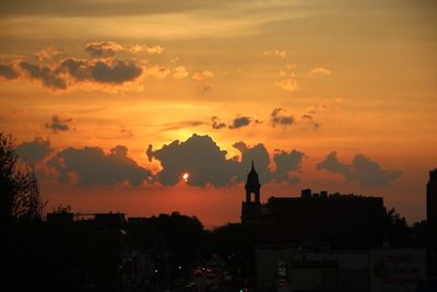 Silhouette statue by buildings against romantic sky at sunset