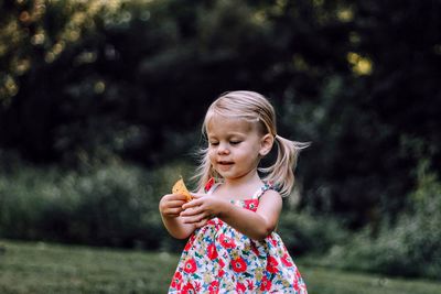 Portrait of cute girl eating apple against tree