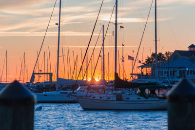 Sailboats moored on sea against sky during sunset