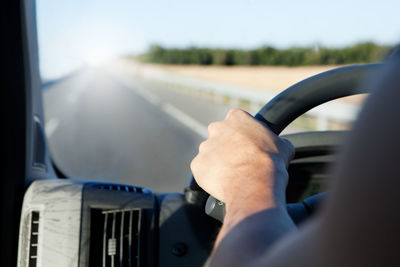 Detail of driver's hand and road