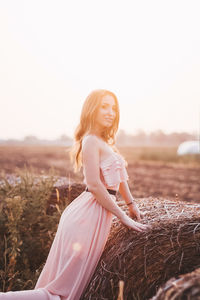 Young woman smiling on field against clear sky