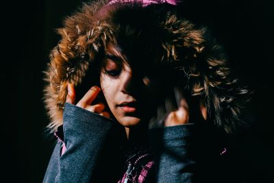 Close-up of woman with fur hood against black background