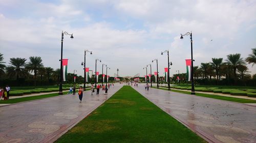 Street lights by footpath in city against sky