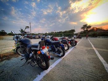 Bicycles parked on road against sky during sunset