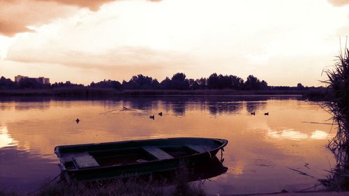 Boats moored in lake against sky during sunset