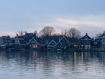 River by houses and buildings against sky