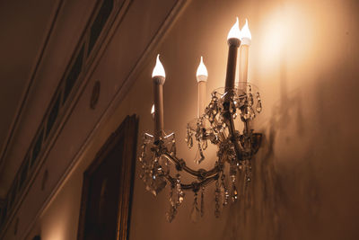 Low angle view of illuminated chandelier hanging on ceiling