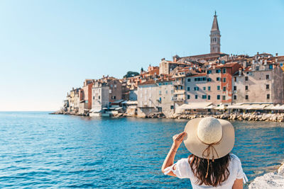 Young woman from behind. picturesque old town by sea in background.