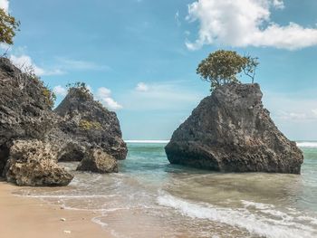 Rock formation on beach against sky