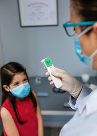 Female doctor looking at infrared thermometer after taking tempe