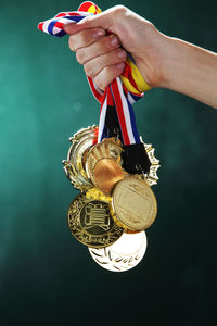 Cropped hand of woman holding medals against wall