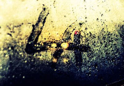 Close-up of wet glass window against sky