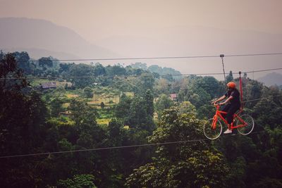 Man riding bicycle on mountain against sky