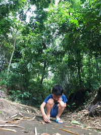 Full length of young man sitting in forest