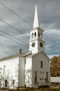 Low angle view of clock tower amidst buildings against sky
