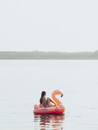 Woman swimming in sea against clear sky