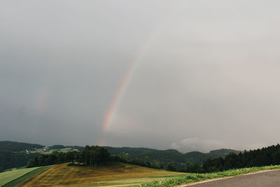 Scenic view of rainbow over field against sky