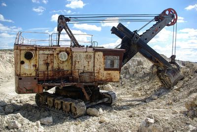 Old machinery at construction site against sky