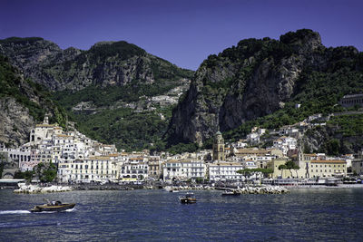 Buildings by sea against mountain