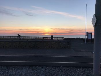 Bridge over road against sky during sunset