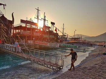 Man at harbor against clear sky during sunset