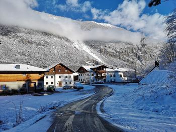 Snow covered houses by road against sky in city