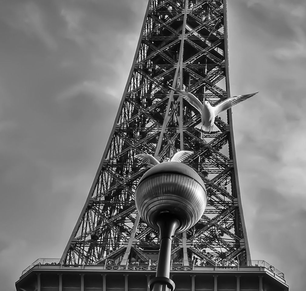 low angle view, built structure, architecture, sky, tall - high, tower, famous place, travel destinations, international landmark, capital cities, metal, tourism, travel, communications tower, cloud - sky, building exterior, eiffel tower, day, metallic, cloud