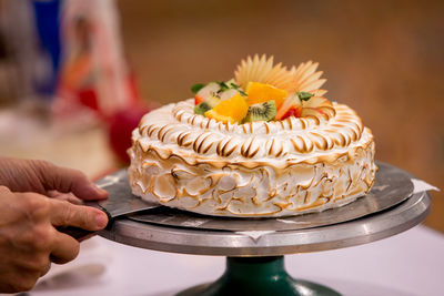 Cropped image of hand holding cake on table
