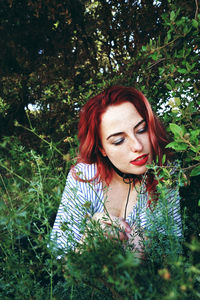 Beautiful young woman with redhead sitting looking plants in park