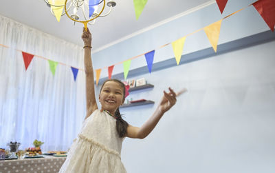 Happy girl holding bubble wand in birthday party at home