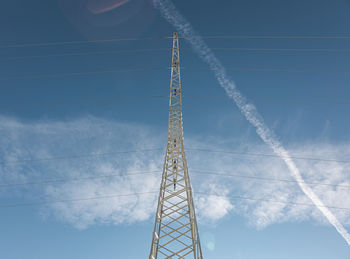 Low angle view of electricity pylon against blue sky