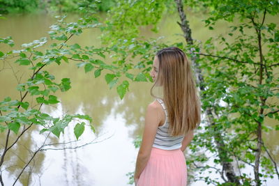 Woman standing by tree against plants